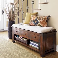 a wooden bench sitting in front of a stair case with pillows on top of it