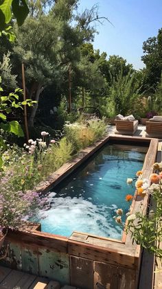 an outdoor hot tub surrounded by flowers and greenery