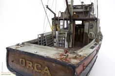 an old wooden boat with rusted paint and writing on the side, in front of a white background