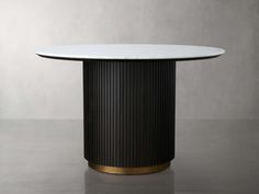 a round dining table with a white marble top and gold trim around the base, on a grey background