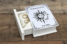 an open box with two wedding rings inside on a wooden table next to some string