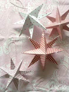 three paper stars on a pink and white tablecloth