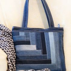 a blue purse sitting on top of a white couch next to a black and white scarf