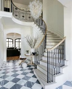 a large foyer with black and white checkered flooring, chandelier and stairs