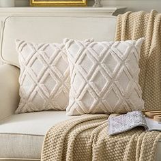 a couch with two pillows on it and a book in front of the pillow case