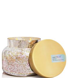 a candle that is sitting next to a container with some gold foil on it and the lid