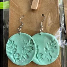 two green clay earrings with leaves on them