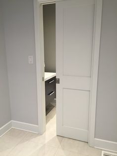 an open door leading to a bathroom with white tile flooring and gray painted walls