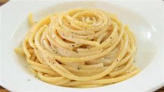 a white bowl filled with pasta on top of a wooden table