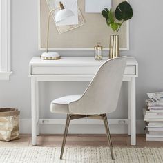 a white desk with a gold lamp and some plants on it next to a chair