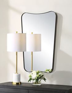 two lamps are on top of a dresser with a mirror and vase in front of it