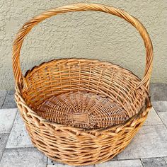 a wicker basket sitting on the ground next to a wall with a tile floor