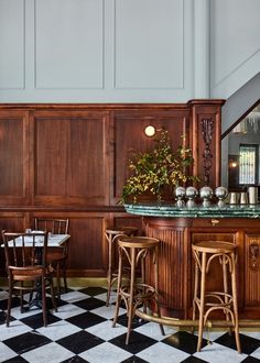 an old fashioned bar with stools and tables in a room that has wood paneling