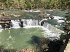 the water is green and flowing down the side of the falls in the woods,