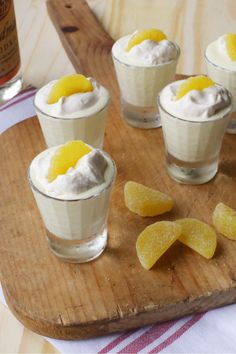 small glasses filled with dessert sitting on top of a wooden cutting board