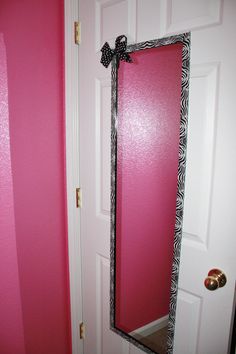 a pink door with a black and white bow hanging on it's side next to a mirror