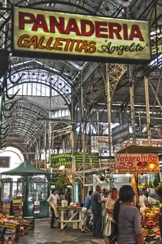 an indoor market with people shopping for fruits and vegetables