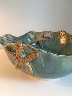 a ceramic bowl with starfishs and seashells in it