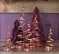 three purple christmas trees with gold ribbons on them