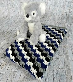 a teddy bear sitting on top of a crocheted blanket