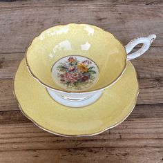 two yellow and white plates with flowers on them sitting on a wooden table next to each other