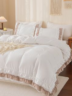 a bed with white comforter and pillows on top of it next to a lamp