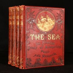 an old red book with gold lettering on the front and back cover, sitting on a black surface