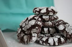 chocolate crinkle cookies piled on top of each other with powdered sugar all over them