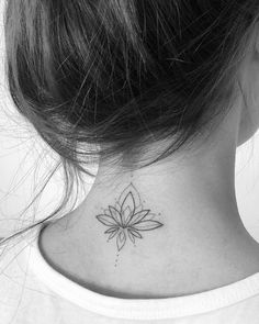 a woman's neck with a small flower tattoo on the back of her neck