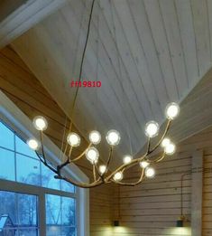 a dining room table and chairs with lights hanging from it's ceiling in front of a large window