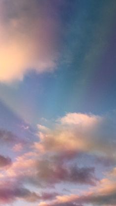 the airplane is flying high in the sky with clouds around it and some people standing on the ground