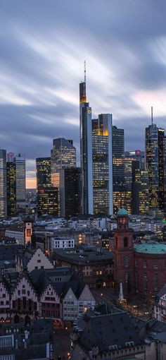 the city skyline is lit up at night, with skyscrapers in the foreground