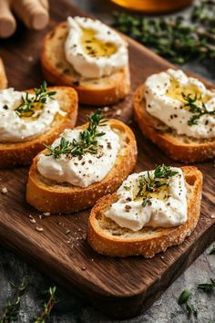 several pieces of bread with cream cheese and herbs on them sitting on a cutting board