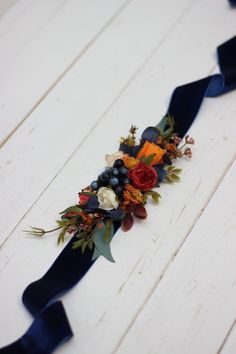 a blue ribbon with flowers and berries is on the floor in front of a white wall