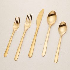 gold flatware is laid out on a white surface