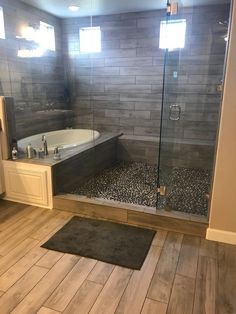 a bathroom with wood flooring and gray tile on the walls, along with a walk in shower