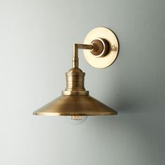 an antique brass wall light on a white wall