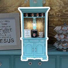 there is a blue cabinet with coffee cups on it and an image of a cross