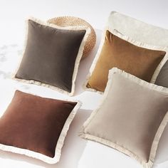 four different colored pillows on a white surface