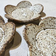 four brown and white bowls sitting on top of a table next to each other with holes in them