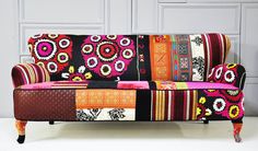 a multicolored patchwork couch sitting on top of a white floor next to a wall