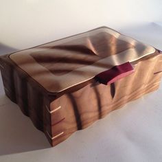 a wooden box sitting on top of a white table next to a red bow tie