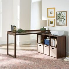 a desk with some books on it in a living room next to a rug and pictures