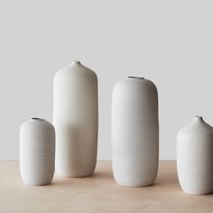 three white vases sitting on top of a wooden table