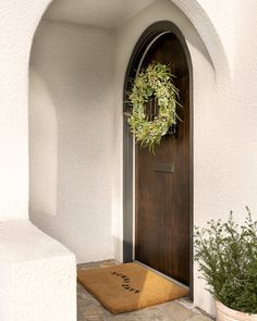 a door with a wreath on it and a welcome mat in front of the door