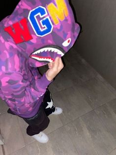 a young child wearing a purple hoodie with a shark head on it's face