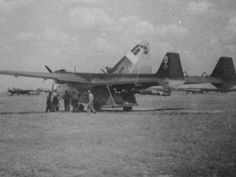 an old black and white photo of people standing in front of a fighter jet on the tarmac