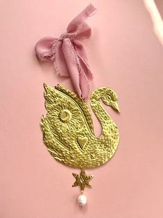 a gold brooch with a pink bow on it's head and a pearl necklace