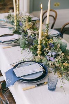 the table is set with blue and white plates, silverware, and flowers on it