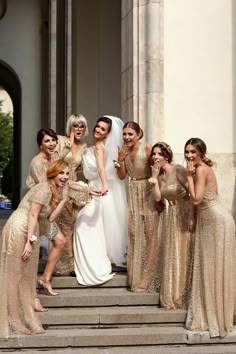 a group of women in gold dresses posing on steps